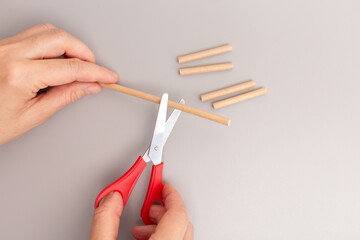 Close up of hand holding scissors cutting paper straw step in creative process DIY quick assembly...