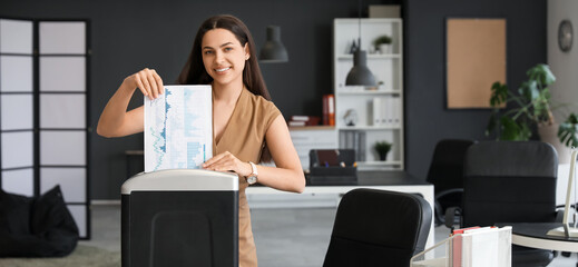 Young secretary destroying documents using shredder in office