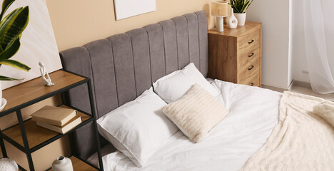 Big comfortable bed with pillows in interior of bedroom