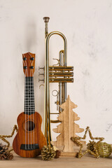 Naklejka premium Composition with ukulele, trumpet and Christmas decorations on wooden table against light background