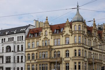 Fototapeta premium Historic European architecture featuring ornate facade with spires and red roof in cityscape, capturing classic design elements of 19th century urban buildings against clear sky background
