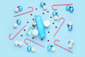 Christmas balls, confetti, candy canes, bottles and jars of cosmetic products on blue background