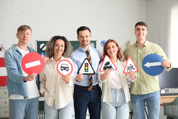 People with instructor and road signs at driving school