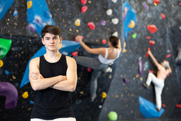 Young man posing with her arms crossed over her chest after climbing class. Artificial black...