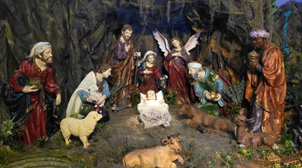 A display showing baby Jesus, Joseph, Virgin Mary, wise man, angel, and lamb. Nativity scene Christmas diorama religious images.