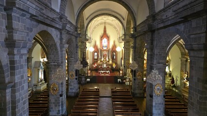 Interior of Catholic Church with columns hidden in darkness and light shining at the altar