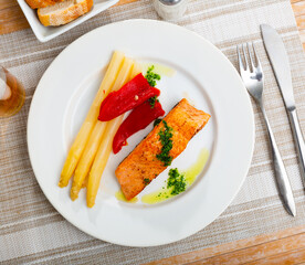 Appetizing Roasted salmon steak with asparagus, pepper and herbs in a cafe