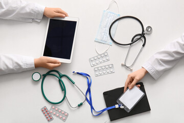 Doctor's hands with tablet and badge on white background