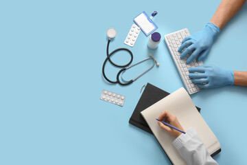 Doctor's hands with computer keyboard and notebook on blue background