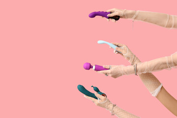Women in laced gloves holding different vibrators on pink background