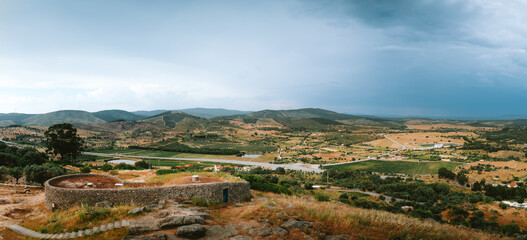 Obraz premium Breathtaking panoramic landscape showcasing the vast meadows, rolling hills, and dramatic cloudy sky in penamacor, portugal, capturing the serene beauty of the region