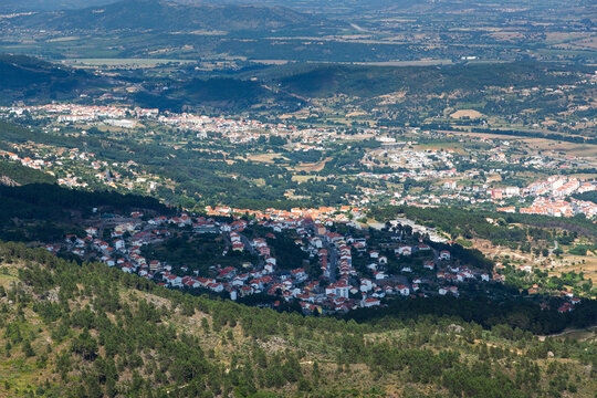 Aerial view of covilha, a city nestled amidst rolling hills and valleys, showcasing the urban sprawl and surrounding landscape under the bright summer daylight of portugal