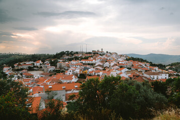 Charming village of penamacor on hill with terracotta roofs and whitewashed walls, surrounded by green hills under dramatic cloudy sky