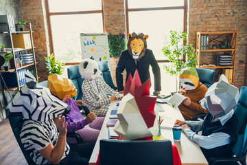 Portrait of rooster panda gorilla lion sloth zebra raccoon mask people gather desk discuss project...