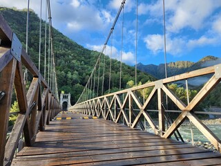 Obraz premium Wooden suspension bridge over the river in the mountains. Beautiful landscape.
