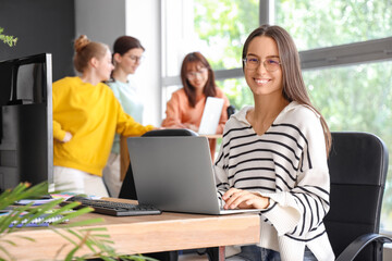 Fototapeta premium Female programmer working with laptop at table in office