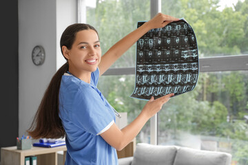 Female doctor studying x-ray image near window in clinic