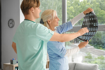 Doctors studying x-ray image near window in clinic