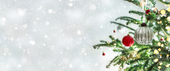 Christmas tree with red Christmas decorations on light background with bokeh, blurred, sparking, glowing. Happy New Year and Xmas card, wide banner