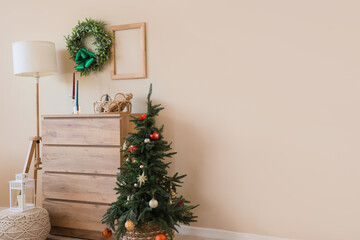Beautiful wreath, Christmas tree, chest of drawers and lamp in room