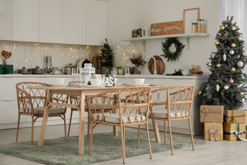 Interior of kitchen with Christmas trees, dining table and glowing lights