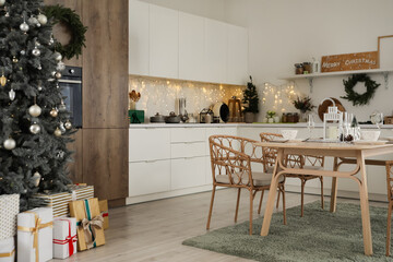 Interior of kitchen with Christmas trees, dining table and glowing lights