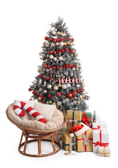 Christmas tree near armchair with pillow in shape of candy, gifts and Santa hat on white background