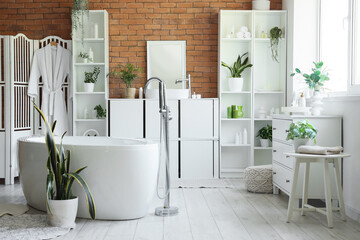 Interior of stylish bathroom with bathtub, sink and shelving unit