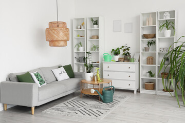 Interior of light living room with sofa, plants and gardening tools