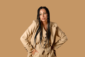 Stylish young African-American woman with braids on beige background