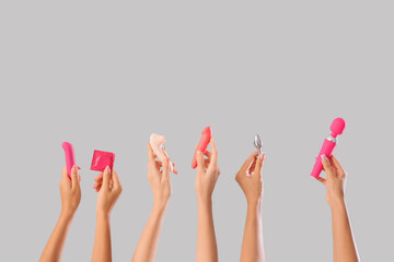 Women with sex toys and condom on grey background