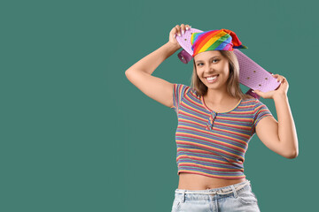 Young woman with skateboard on green background