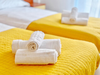 Clean Fresh Fluffy White Towels on Yellow Bed in Hotel Apartments