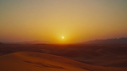 A beautiful desert sunset with rolling sand dunes and mountains in the distance.