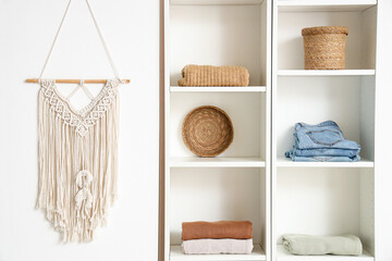 Shelving unit with clothes, baskets and decor hanging on light wall