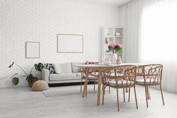 Interior of dining room with sofa and protea flowers in vase on table