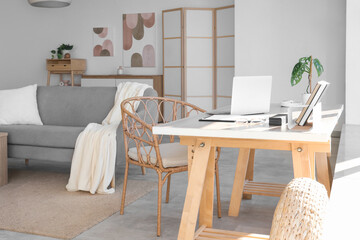 Workplace with laptop and notebooks in light living room