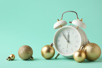 Composition with alarm clock and Christmas balls on turquoise background