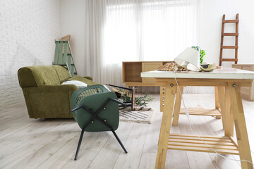 Interior of messy living room with sofa and overturned chair after earthquake