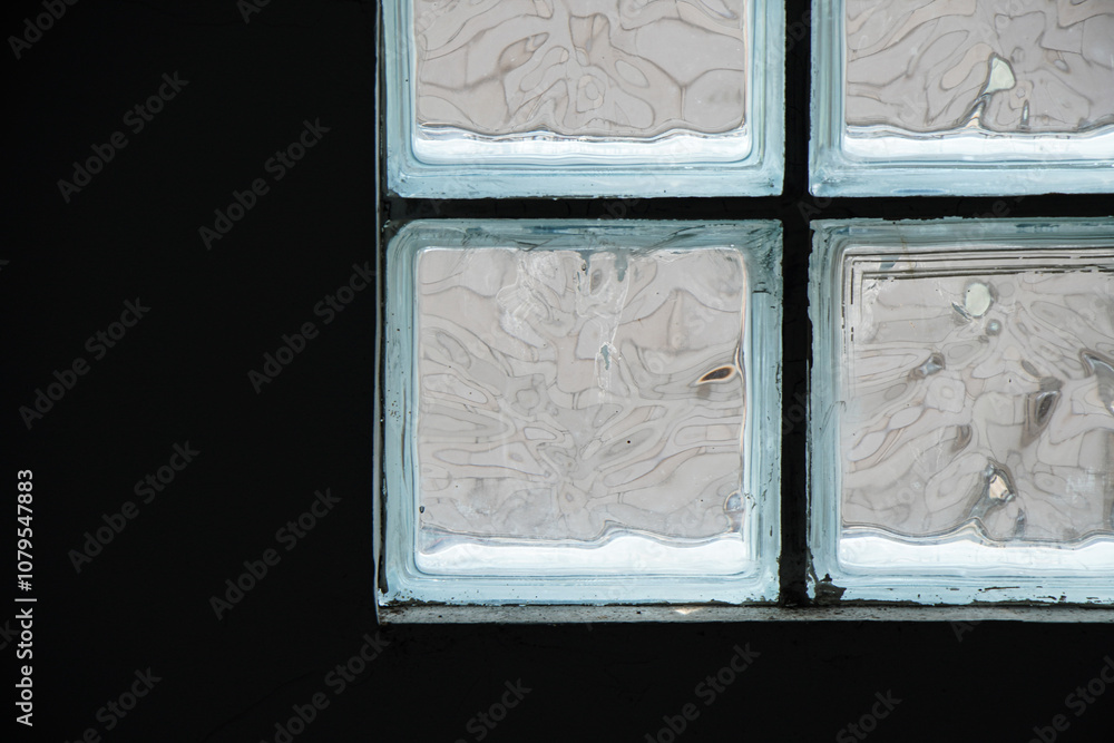 Poster a close-up view of a glass block window, featuring its textured surface and framing. a window of fro