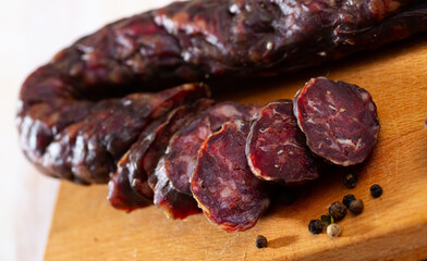 Spicy dry cured sausage with liver from on wooden background. Traditional French meat products