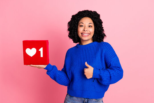 Photo young lady wearing blue knitted sweater promoting showing like symbol holding red subscription button isolated on pink color background