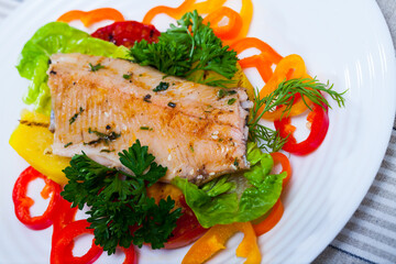 Tasty fried trout fillets, served with vegetables and greens at plate