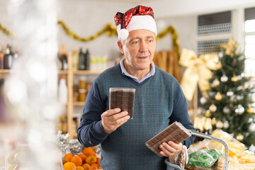 Portrait of elderly man buying chocolate and chocolate candies for gift and celebrating Christmas