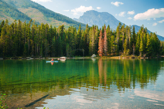 The woman is paddleboarding on Leigh Lake in Grand Teton National Park