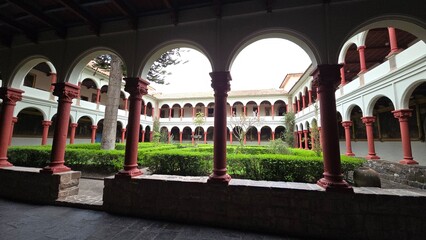 Quad cloister of Christian Catholic monastery with red columns and green hedge