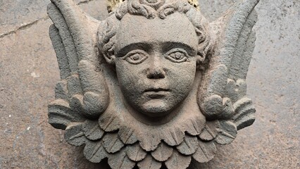 Stone carved face of a boy child angel with wings