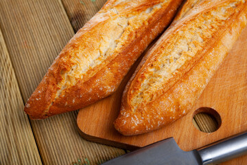 Freshly baked white baguette on wooden background