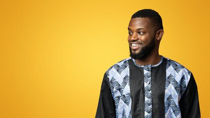 Handsome black guy in african traditional shirt looking at copy space over pink studio background, panorama. Cheerful african american young man staring at empty space for text or advertisement