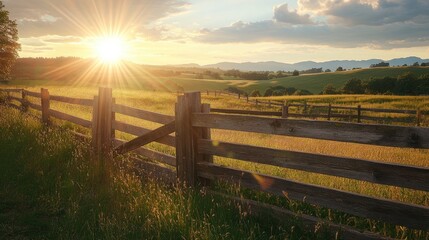 Fototapeta premium Scenic rural landscape featuring an old wooden fence illuminated by sunlight with a sunburst on the horizon
